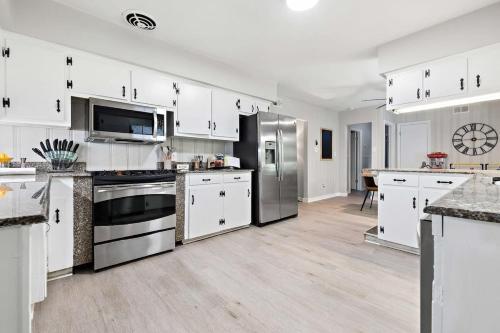 モービルにあるThe Ranch 4-Bedrooms Large Yard & Patioの白いキャビネットとステンレス製の電化製品を備えたキッチン