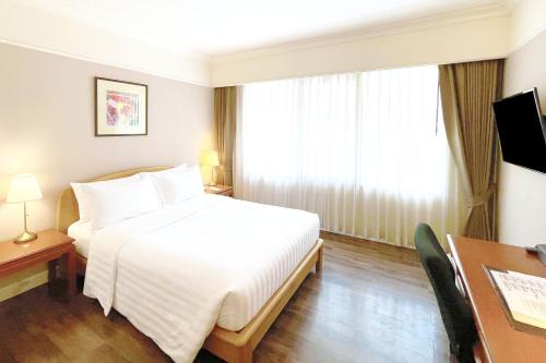 a hotel room with a white bed and a desk at Le Siam Hotel Silom Bangkok by PCL in Bangkok