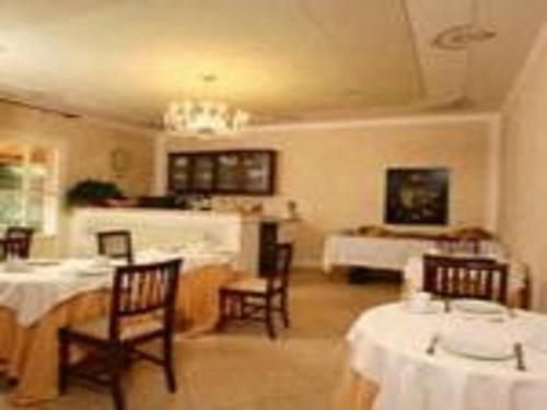 a dining room with tables and chairs and a kitchen at Il Melograno Country House in Saturnia