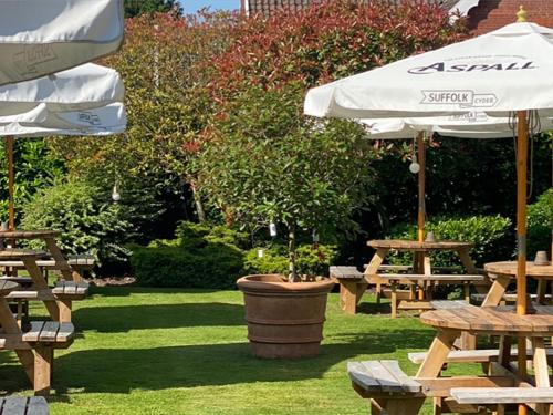 a group of picnic tables and an umbrella at Mulberry Tree in Attleborough