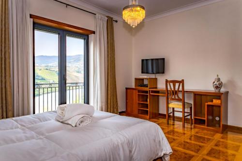 a bedroom with a bed and a desk with a window at Fraga Douro House, Douro Valley in Resende