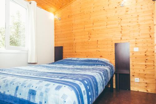 サン・ドニ・ドレロンにあるTerres de France - Les Hameaux des Marinesの木製の部屋にベッド1台が備わるベッドルーム1室があります。