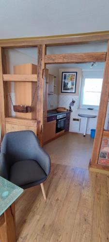 a living room with a blue chair and a kitchen at Ferienwohnung Weise in Grillenberg