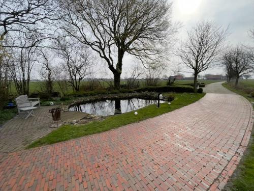 a brick walkway with a pond in a park at Ferienwohnung im Schafhaus in Wangerland