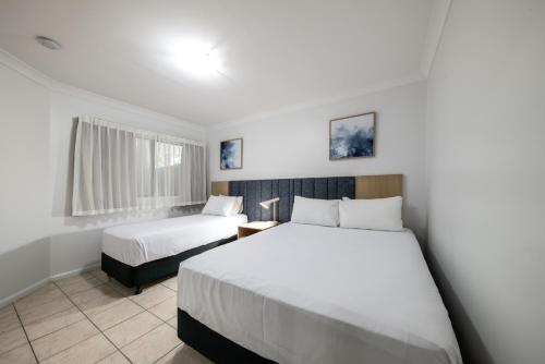 una camera d'albergo con due letti e una finestra di at Water's Edge Resort ad Airlie Beach