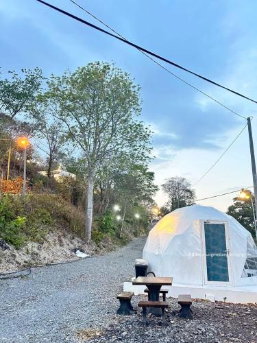 a tent and a picnic table on a gravel road at Gunung Medan Glamping & Cafe in Kangar