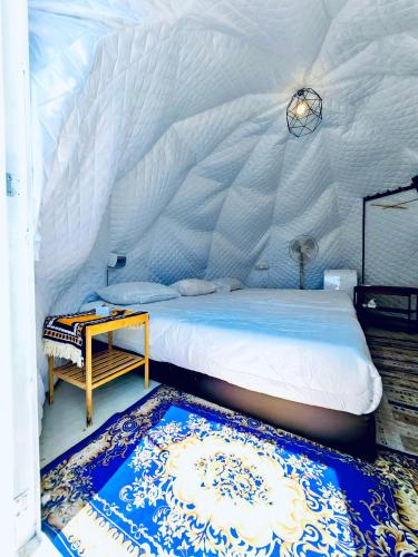 a bedroom with a bed and a table and a rug at Gunung Medan Glamping & Cafe in Kangar