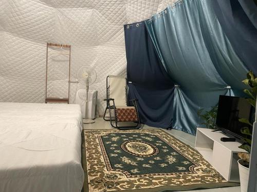 a bedroom with a bed and a rug and a tv at Gunung Medan Glamping & Cafe in Kangar