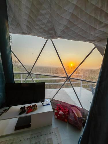 a room with a desk with a view of the sunset at Gunung Medan Glamping & Cafe in Kangar