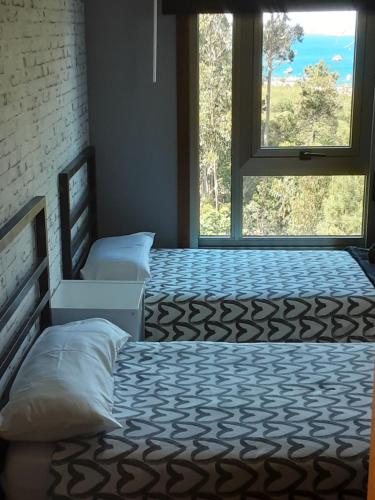 a bedroom with two beds and a window with a view at O IGREXARIO in Cangas de Morrazo
