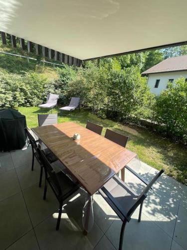 a wooden table and chairs on a patio at T3, à 5 min à pied du lac Annecy in Duingt