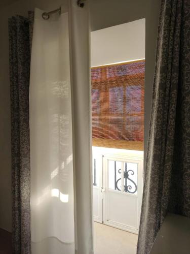 una ventana en una habitación con una cortina blanca en Casa Correos en Medina Sidonia
