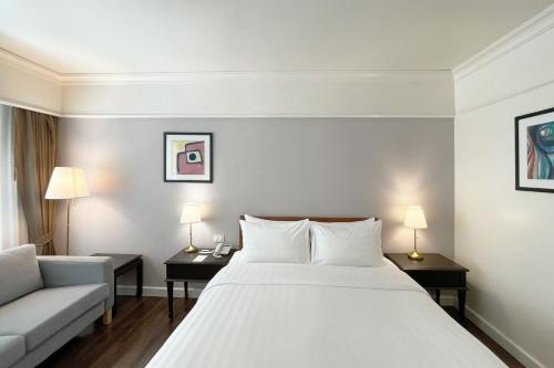 a bedroom with a large white bed and a couch at Le Siam Hotel Silom Bangkok by PCL in Bangkok