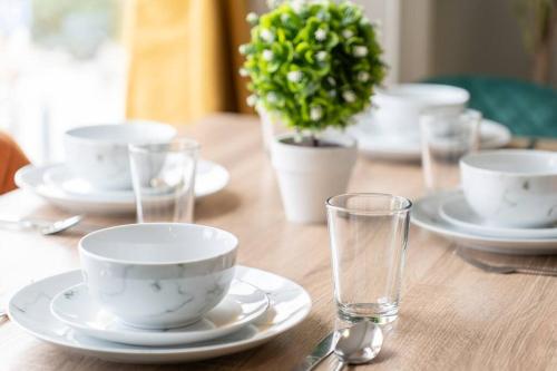 una mesa de madera con tazas blancas, platos y vasos en Open Mind Property - Cosy Flat in Southsea en Portsmouth