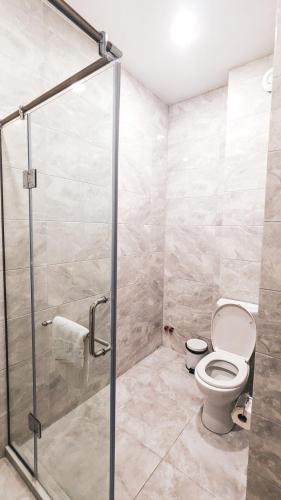 a bathroom with a toilet and a glass shower stall at GG ApartHotel in Batumi