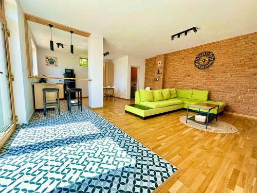 - un salon avec un canapé vert et un mur en briques dans l'établissement Casa Aluna Duo, à Sohodol