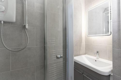 a bathroom with a shower and a sink and a mirror at Beautiful 1 bedroom ground floor new apartment in old Cornwall in St. Just