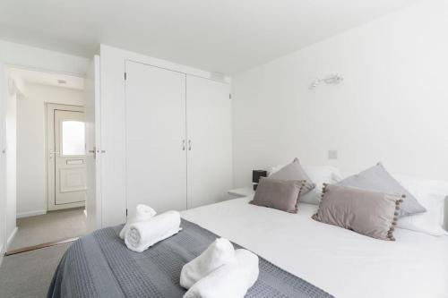a white bedroom with a large white bed with pillows at Beautiful 1 bedroom ground floor new apartment in old Cornwall in St. Just