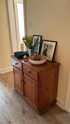 a wooden cabinet with a bowl of fruit on top of it at Palm Tree Apartment- Period Home with Cat in Edinburgh