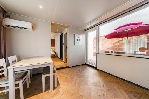 a dining room with a table and a pink umbrella at Browndot Samcheonpo in Sacheon