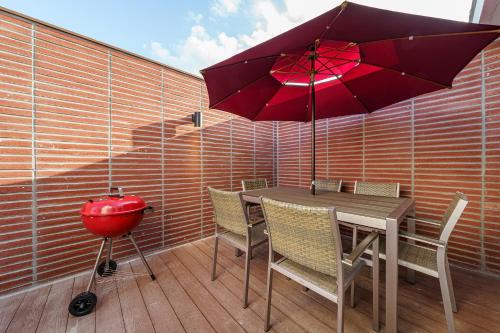 a table and chairs with a red umbrella and a grill at Browndot Samcheonpo in Sacheon