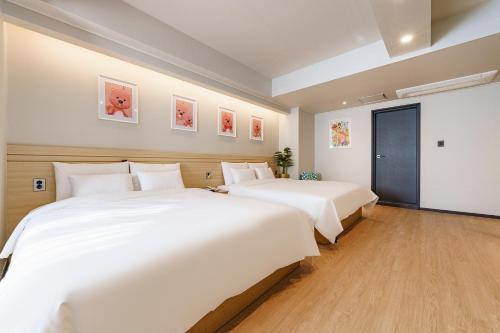 two beds in a hotel room with white sheets at Browndot Samcheonpo in Sacheon
