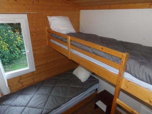 Ce lit superposé se trouve dans une cabine dotée d'une fenêtre. dans l'établissement Terres de France - Les Hameaux de Miel, à Beynat