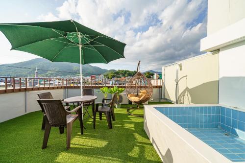a patio with a table and an umbrella on a balcony at Browndot Samcheonpo in Sacheon