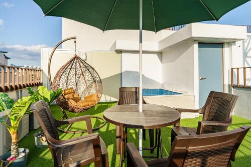 a patio with a table and chairs and an umbrella at Browndot Samcheonpo in Sacheon
