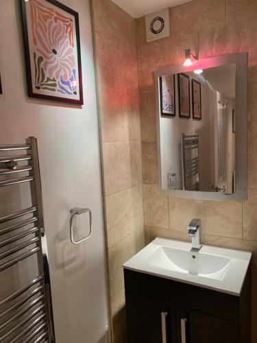 Luxury Putney Riverside Apartment في لندن: حمام مع حوض ومرآة