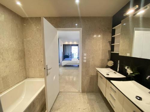 une salle de bain avec une baignoire et un lavabo et une baignoire dans l'établissement Cannes Croisette - Appartement 3 Pièces Résidence GRAY D'ALBION, à Cannes