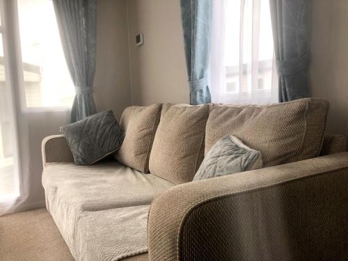un sofá en una sala de estar con cortinas azules en A Sea View Scene - Ocean Edge Holiday Park, en Heysham