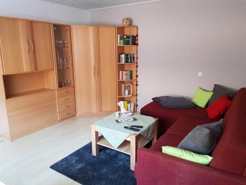 uma sala de estar com um sofá vermelho e uma mesa em Ferienwohnung Witt em Neustrelitz