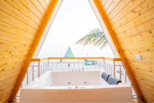 a large bath tub in a room with a large window at Agonda Palm Beach Resort in Agonda