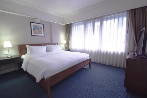 a hotel room with a large bed and a window at Le Siam Hotel Silom Bangkok by PCL in Bangkok