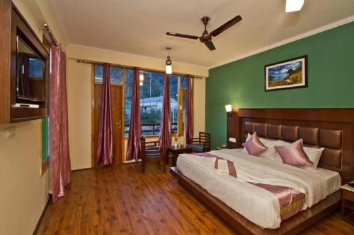 ein Schlafzimmer mit einem Bett und einer grünen Wand in der Unterkunft Hotel Tribhuvan Ranikhet Near Mall Road - Mountain View -Parking Facilities - Excellent Customer Service Awarded - Best Seller in Rānīkhet