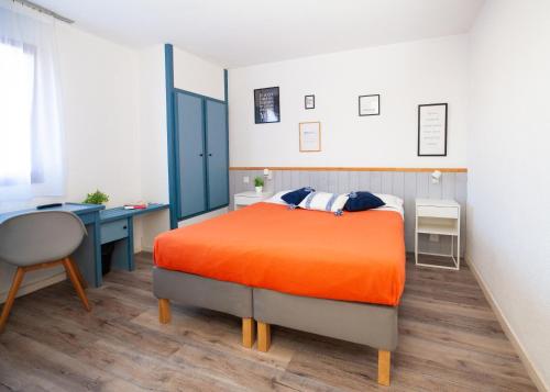 - une chambre avec un lit orange et un bureau dans l'établissement Hotel Atlantide, à Biscarrosse