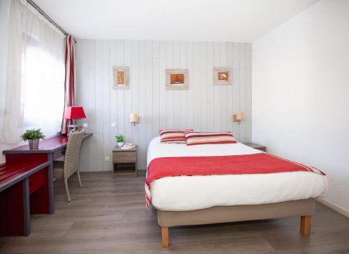 a bedroom with a bed and a desk and a desk at Hotel Atlantide in Biscarrosse