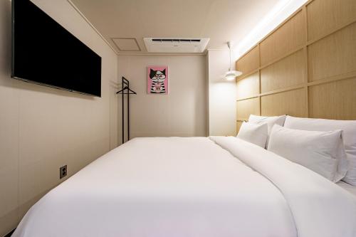 a bedroom with a white bed and a flat screen tv at Browndot Samcheonpo in Sacheon