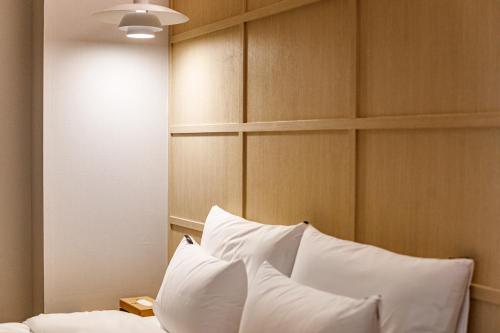 a bedroom with white pillows on a bed at Browndot Samcheonpo in Sacheon