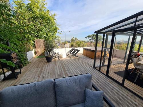 un salon avec un canapé sur une terrasse en bois dans l'établissement Magnifique appartement - SPA privé - Terrasse, à La Mulatière