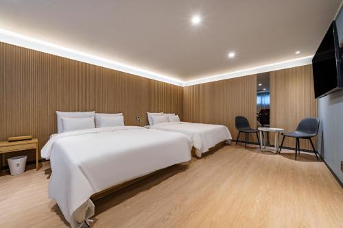 a hotel room with two beds and a flat screen tv at Browndot Samcheonpo in Sacheon
