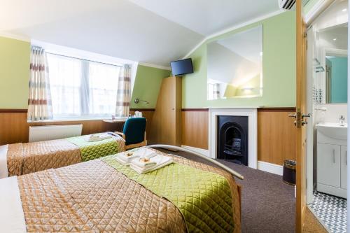 a hotel room with two beds and a fireplace at Gower House Hotel in London