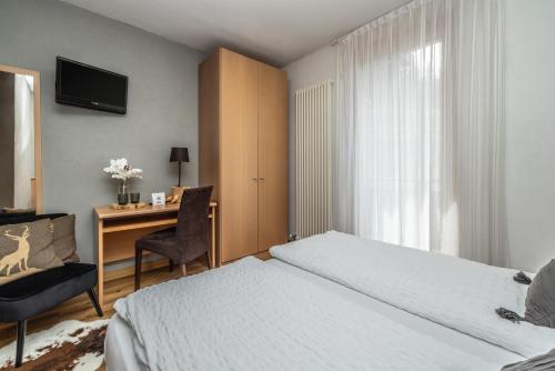 a bedroom with a bed and a desk with a chair at Hotel Folgarida in Folgarida