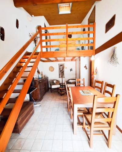 a room with a wooden staircase and a table and chairs at La Tiloé des dunes ~ T3 centre de la Palmyre in Les Mathes