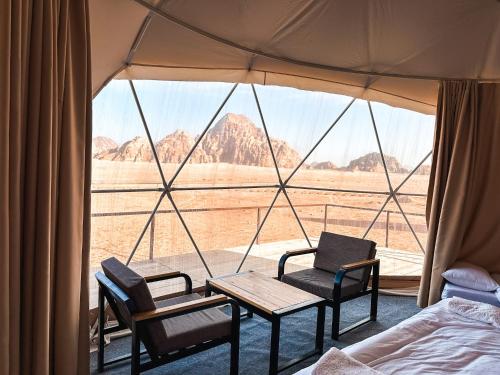 a tent with a bed and two chairs and a table at Mirage Camp Wadi Rum in Wadi Rum