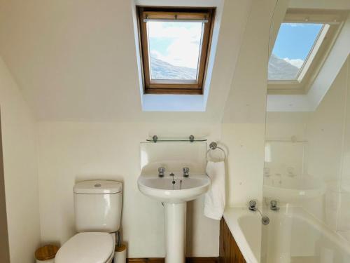 a white bathroom with a toilet and a sink at Avoca House in Fort William