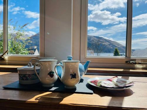 a table with two tea pots and a plate of food at Avoca House in Fort William