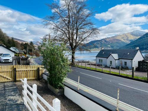 a white fence next to a road and a house at Avoca House in Fort William