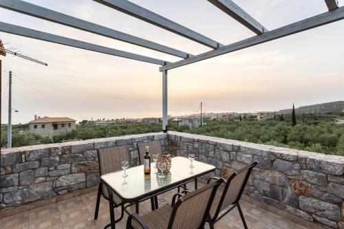 a patio with a table and chairs and a stone wall at Mani Stone Villa Majlinda - Tranquil Getaway Gem in Riglia